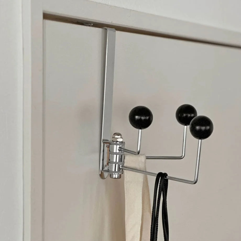 Detailed shot of the hinge mechanism and polished chrome finish of the black door hook - RoomDen
