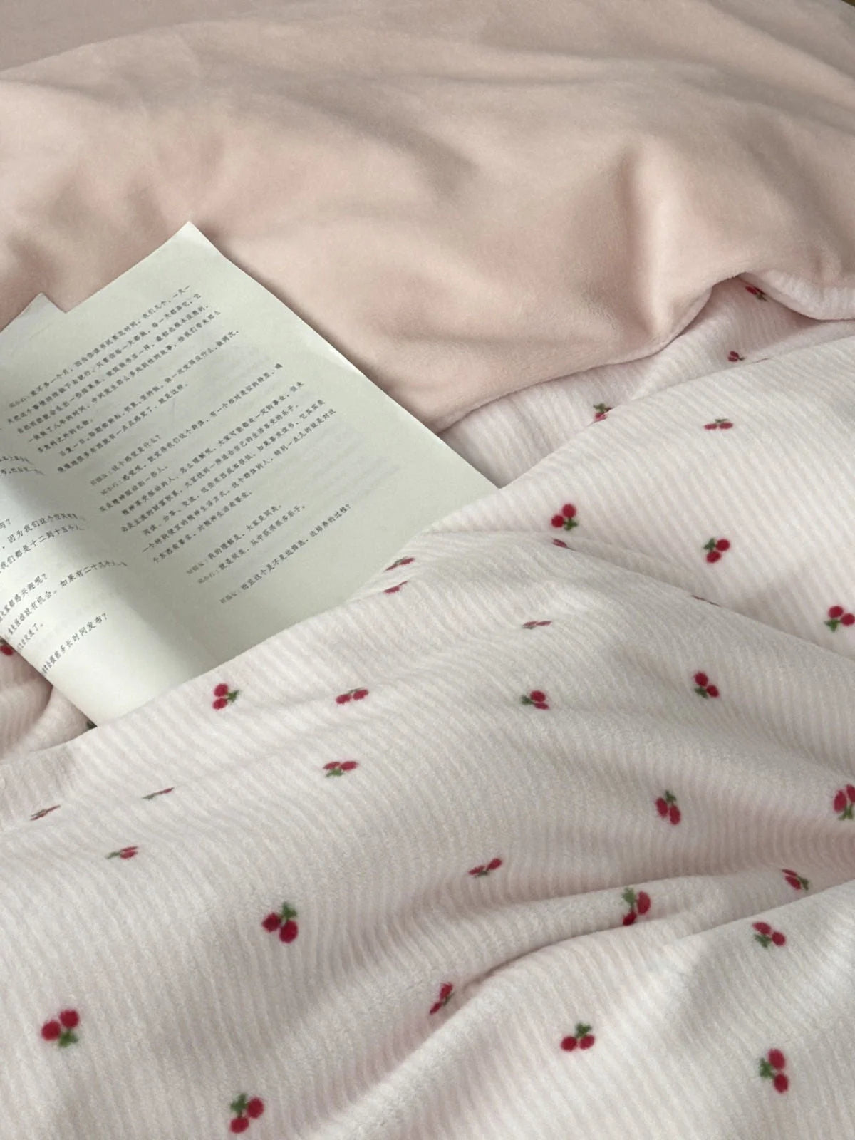 Close-up detail of the soft pink flannel fleece and ditsy cherry pattern with a book resting on the duvet. - RoomDen