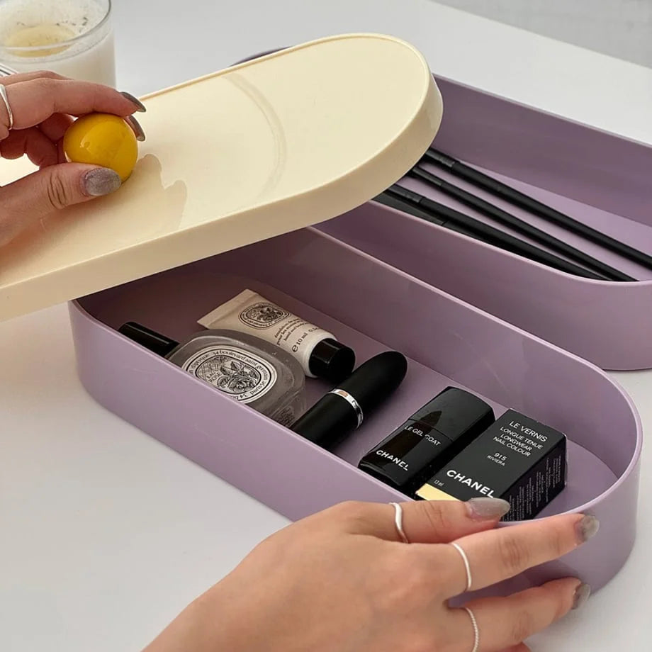 Close-up of the bottom tray of the organizer filled with cosmetics, with a hand holding the lid.