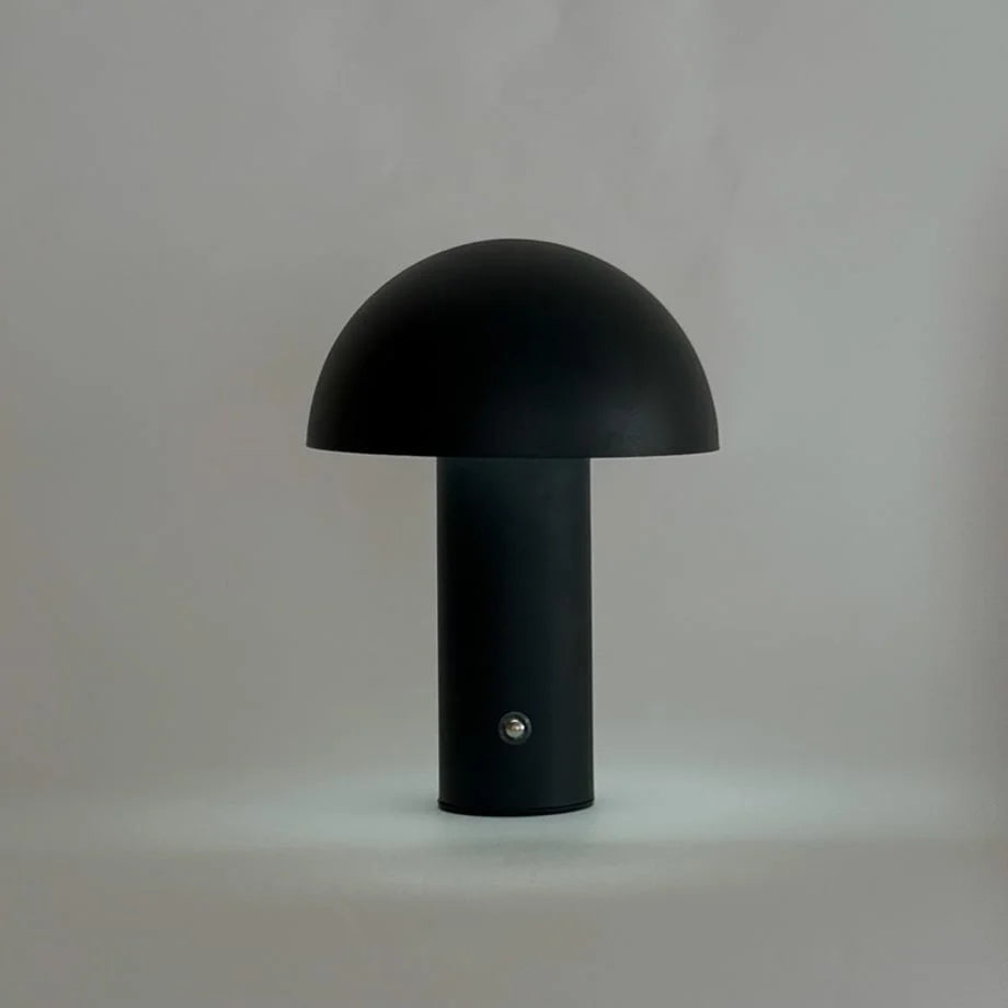 Front view of the black metal mushroom lamp against a plain light grey background, unlit - RoomDen.