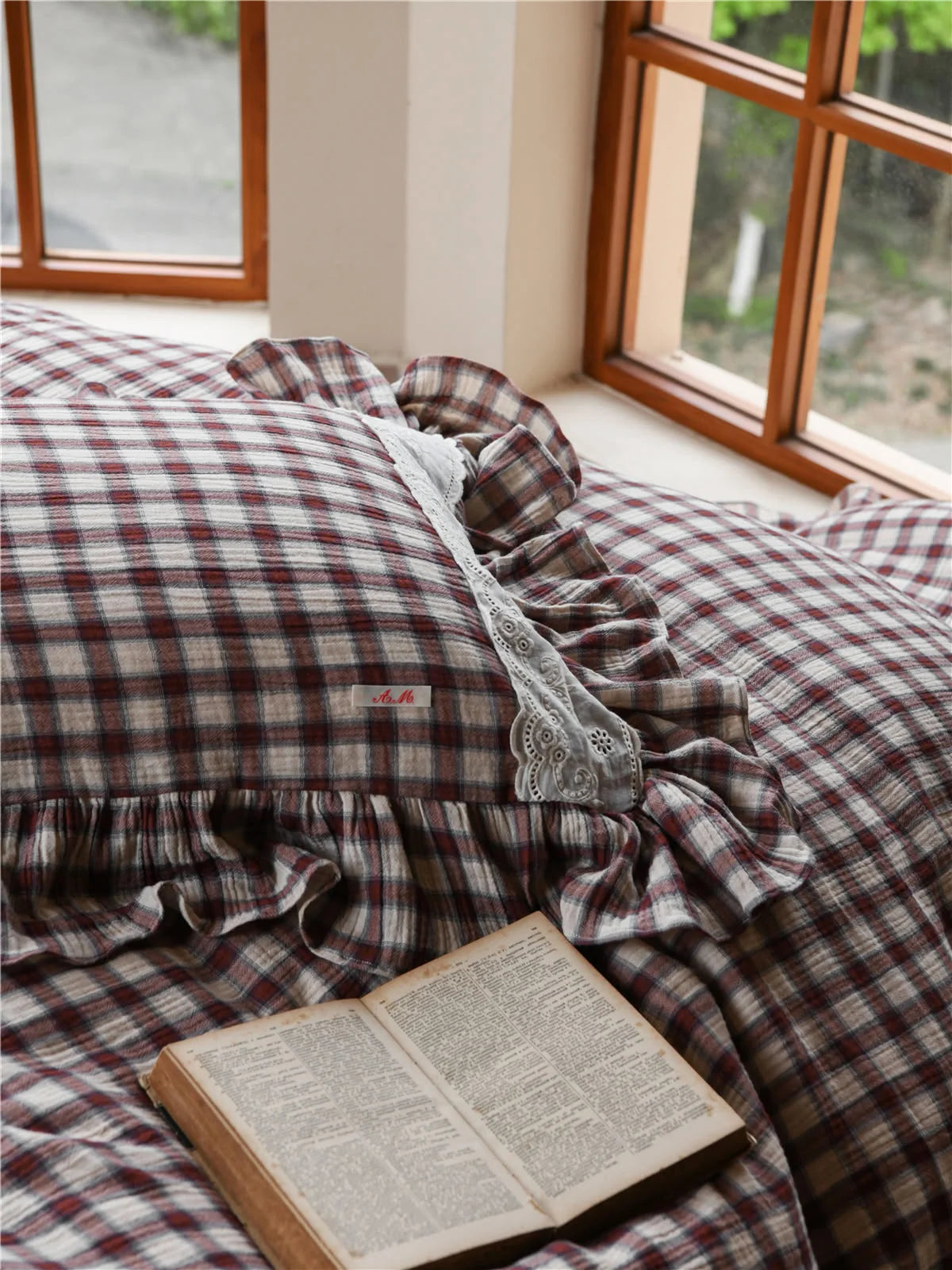 Close-up of the Brown Gingham bedding with an open vintage book resting on it.