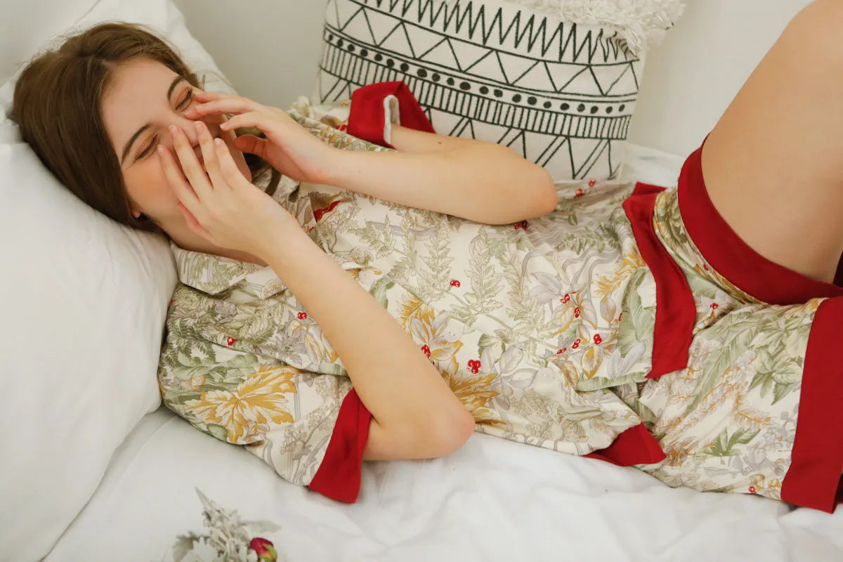 RoomDen Silky Festive Berry Botanical Cotton Sateen Pajama Set - Laughing Model Lying Down - Soft Sleepwear