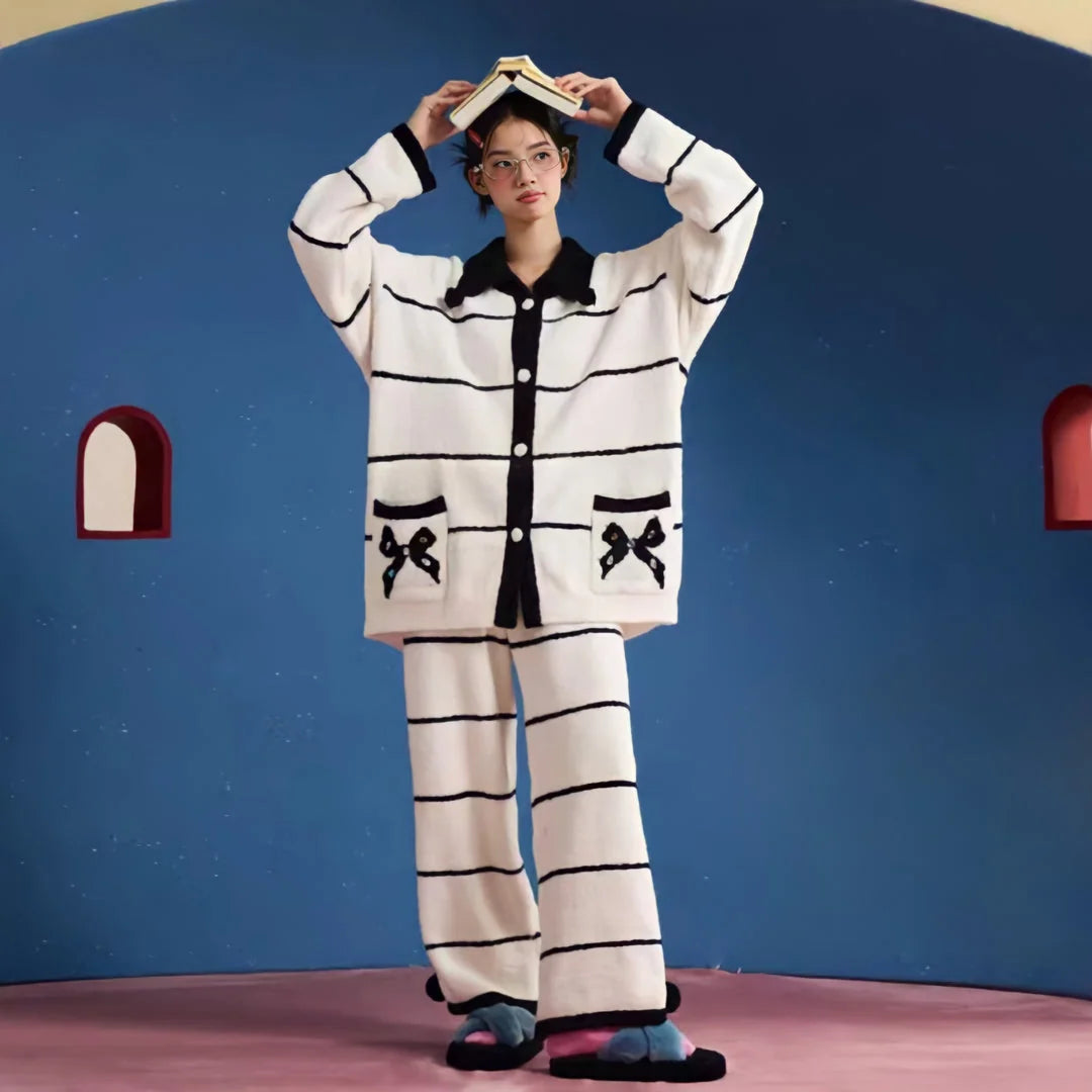 Full view of a model wearing the Plush Striped Fleece Pajama Set with bow details, posing with a book on her head - RoomDen.