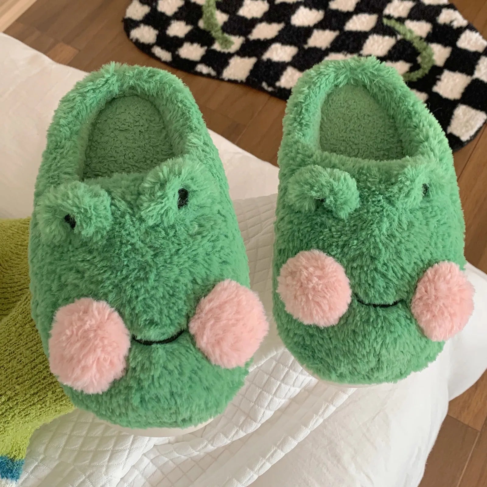 Close up detail of green plush texture and pink cheeks on frog slippers - RoomDen