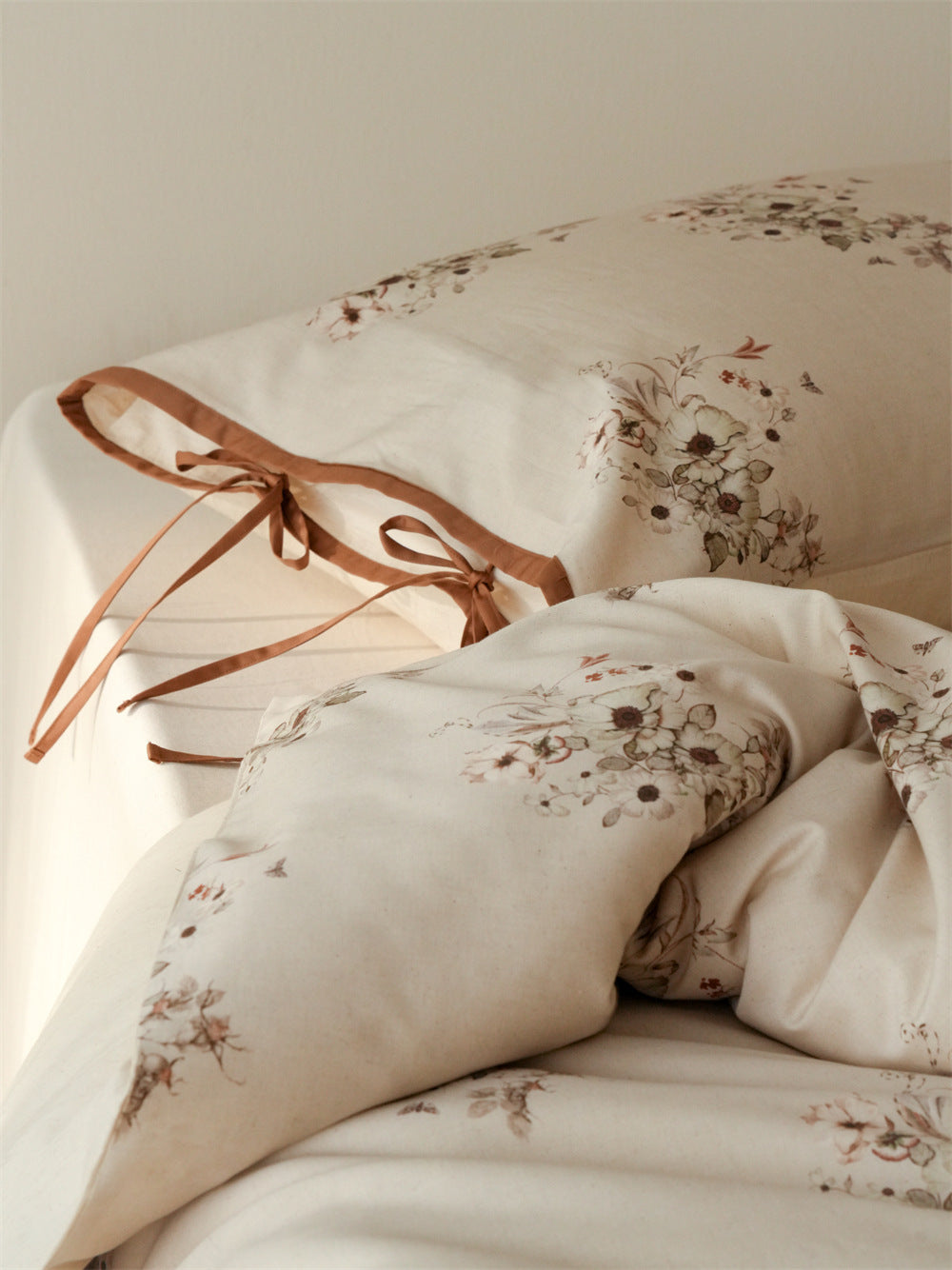 Stillgarden Butterfly Posy Cotton Linen Bedding Set – Caramel edging and ties on a pale floral pillow - Roomden