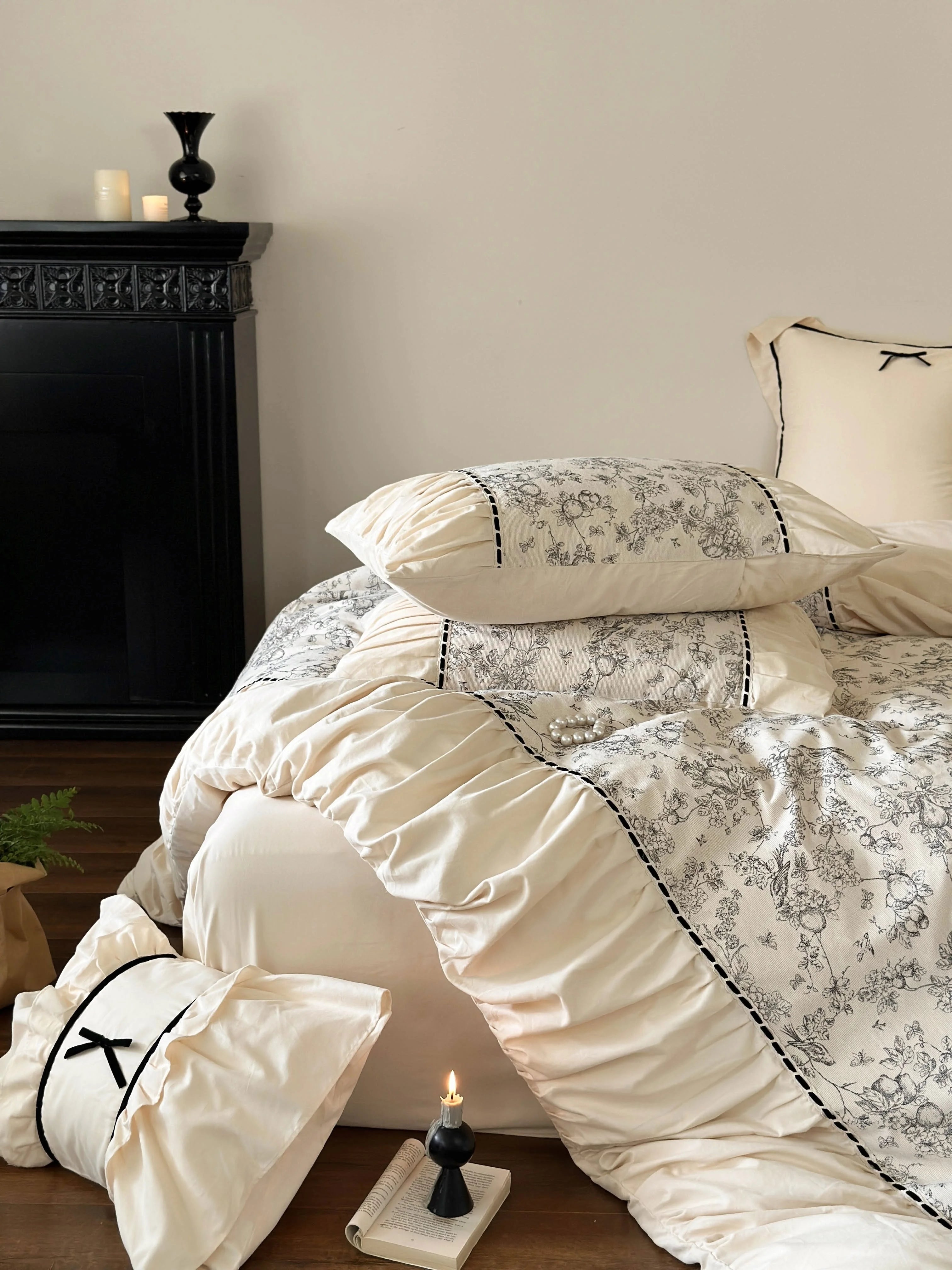The Cream Toile bedding set styled with a candle and book, creating a Light Academia vibe. - RoomDen