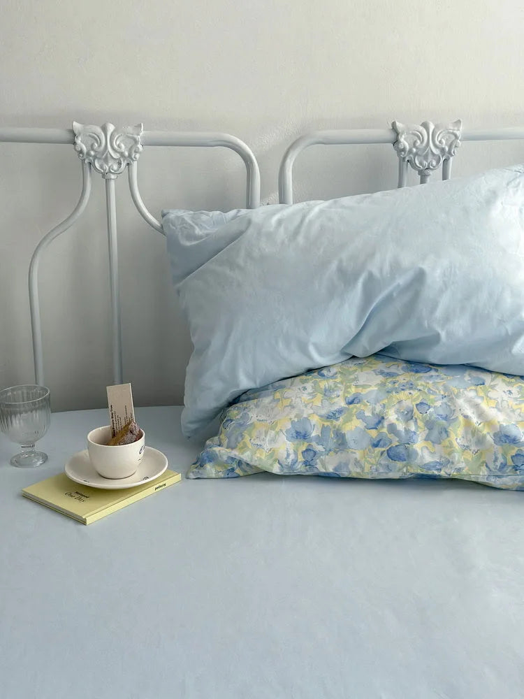 Minimalist styling of the bedding, with a solid blue pillowcase and sheet visible under the floral pillow.