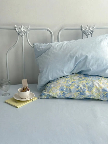 Minimalist styling of the bedding, with a solid blue pillowcase and sheet visible under the floral pillow.
