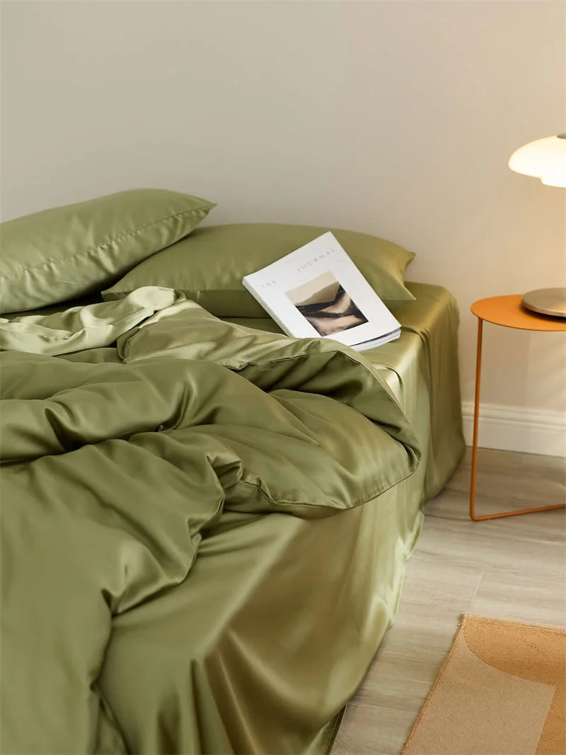 Side view of the bed with the olive green Tencel duvet cover cascading down, next to a modern side table and lamp - RoomDen.