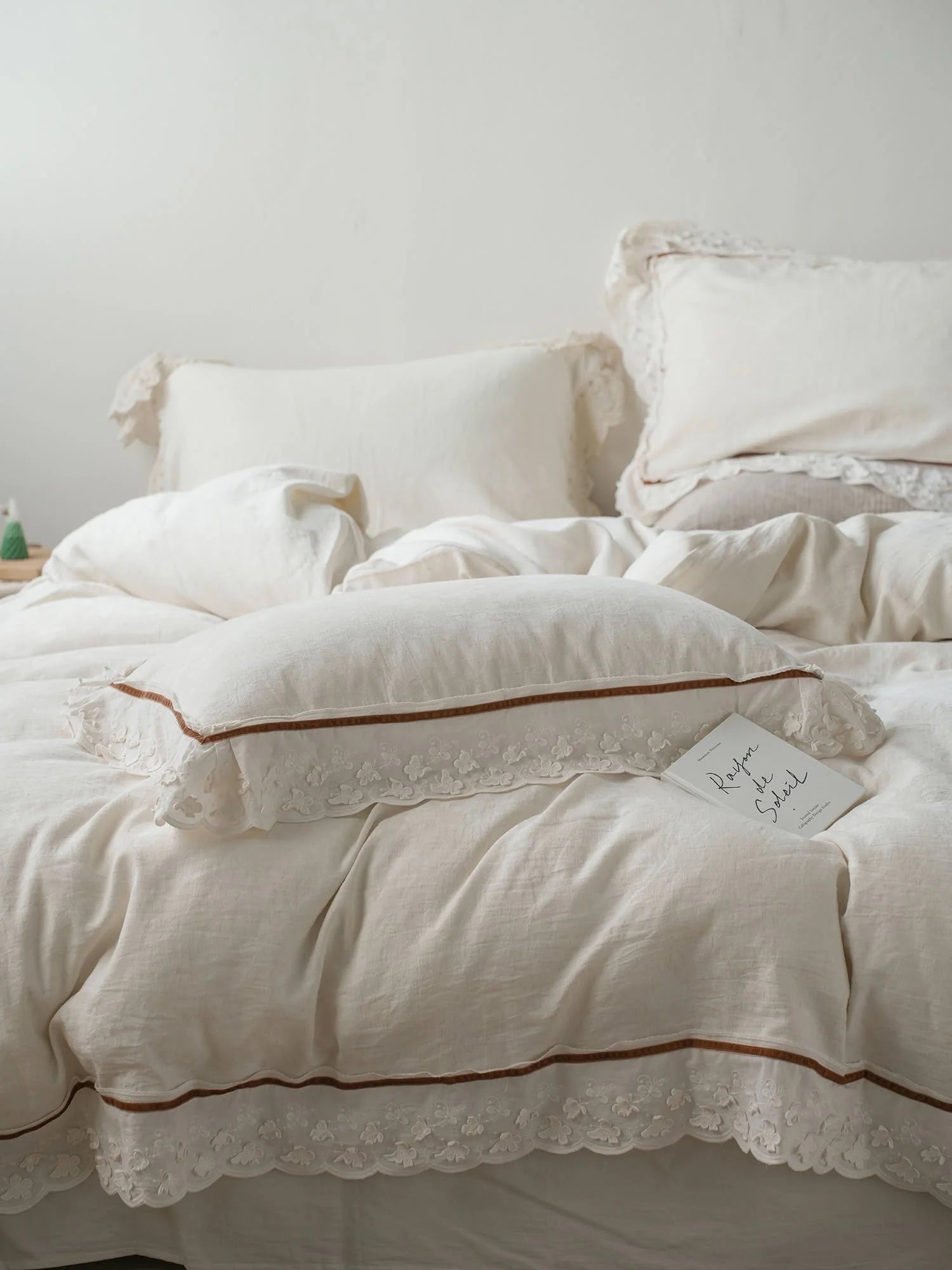 Close-up of the pillowcases and duvet cover, showcasing the delicate brown trim and white floral lace ruffle detail. - RoomDen