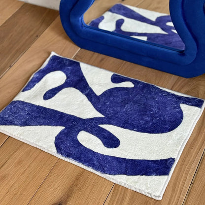 RoomDen abstract rug shown in a blue and white color variation reflected in a blue wavy mirror