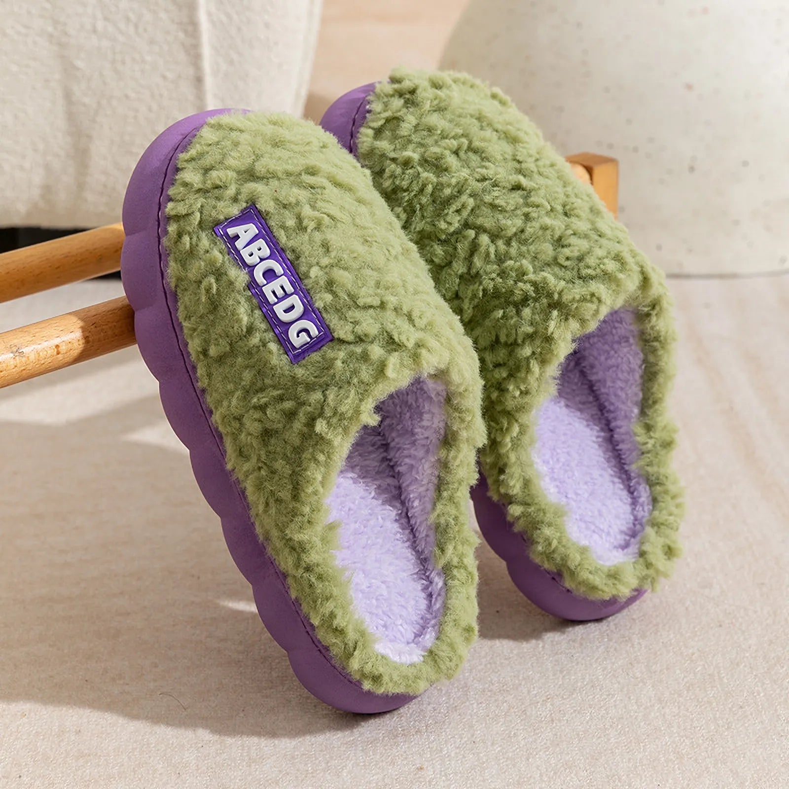 Green upper with purple sole plush house slippers hanging on wooden rack - RoomDen