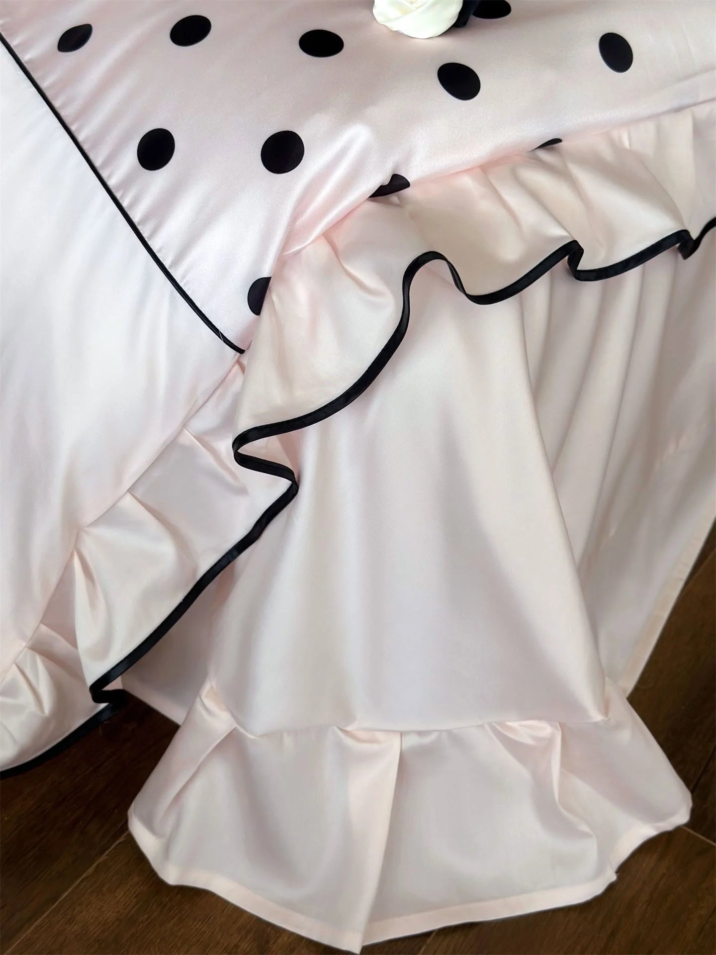 Close-up detail of the black-trimmed ruffles on the Blush Pink & Black Polka Dot bed skirt - RoomDen.