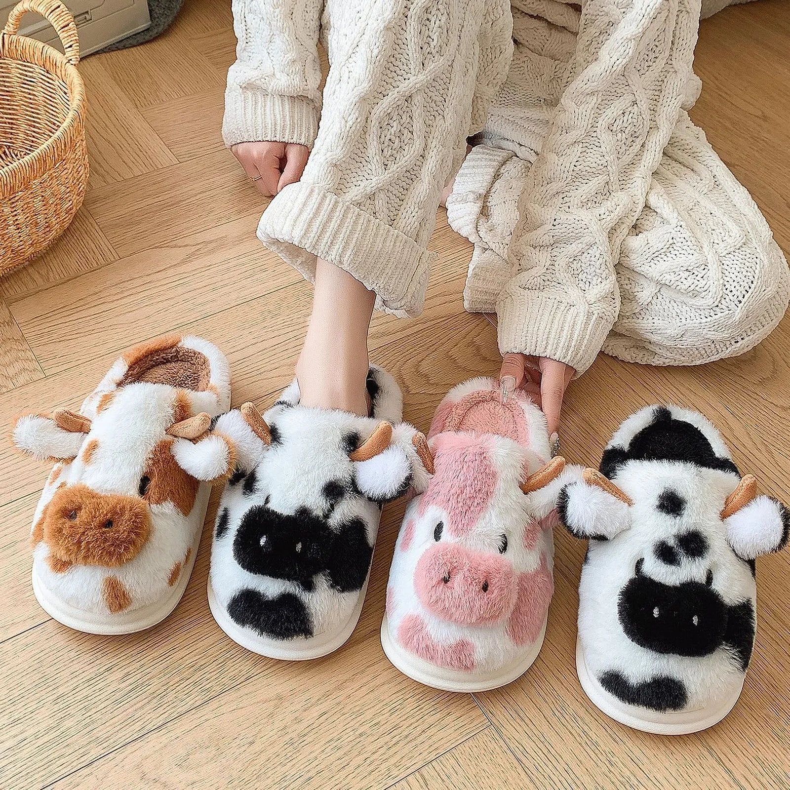 Lifestyle view of model wearing mismatched Brown and Black Cow Print slippers on wooden floor.