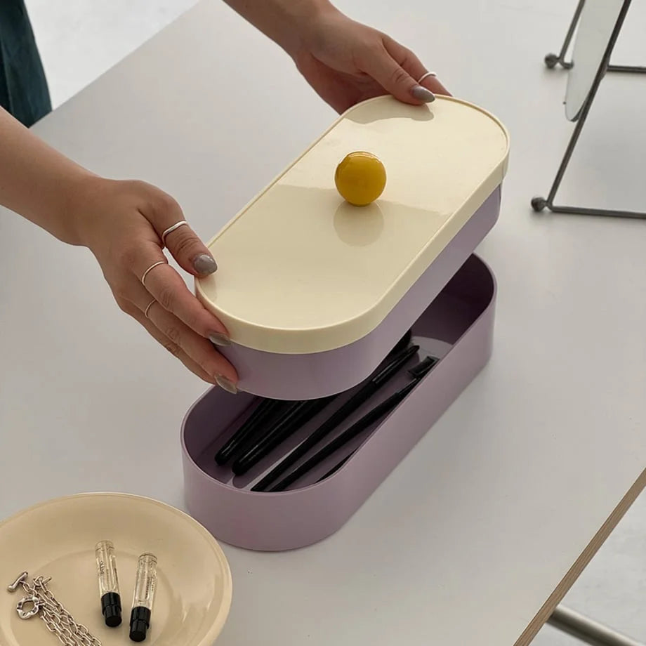 Hands separating the two stackable lavender trays of the makeup organizer.
