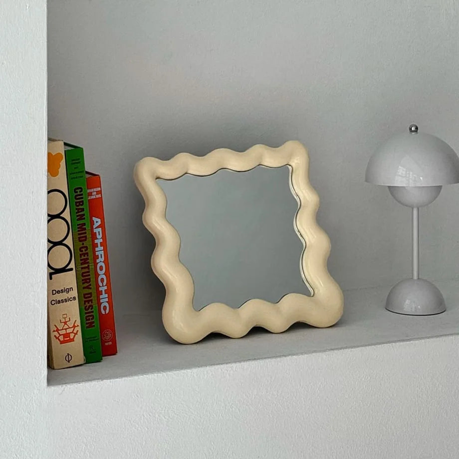 Close-up of the cream irregular shape mirror on a shelf, highlighting its smooth, glossy finish - RoomDen