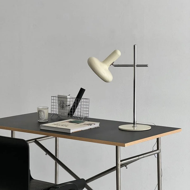 Wide view of the cream Smooth Sculptural Metal Accent Lamp on a desk with a wire basket and candle — RoomDen