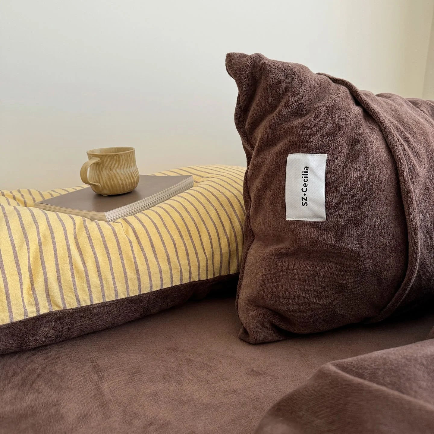Detail shot of the brown fleece pillowcase next to the yellow striped pillowcase.