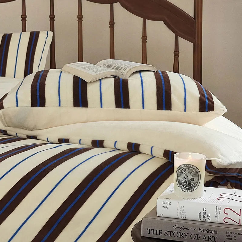 A book resting on the cream and brown striped velvet pillow, highlighting its cozy vibe - RoomDen.