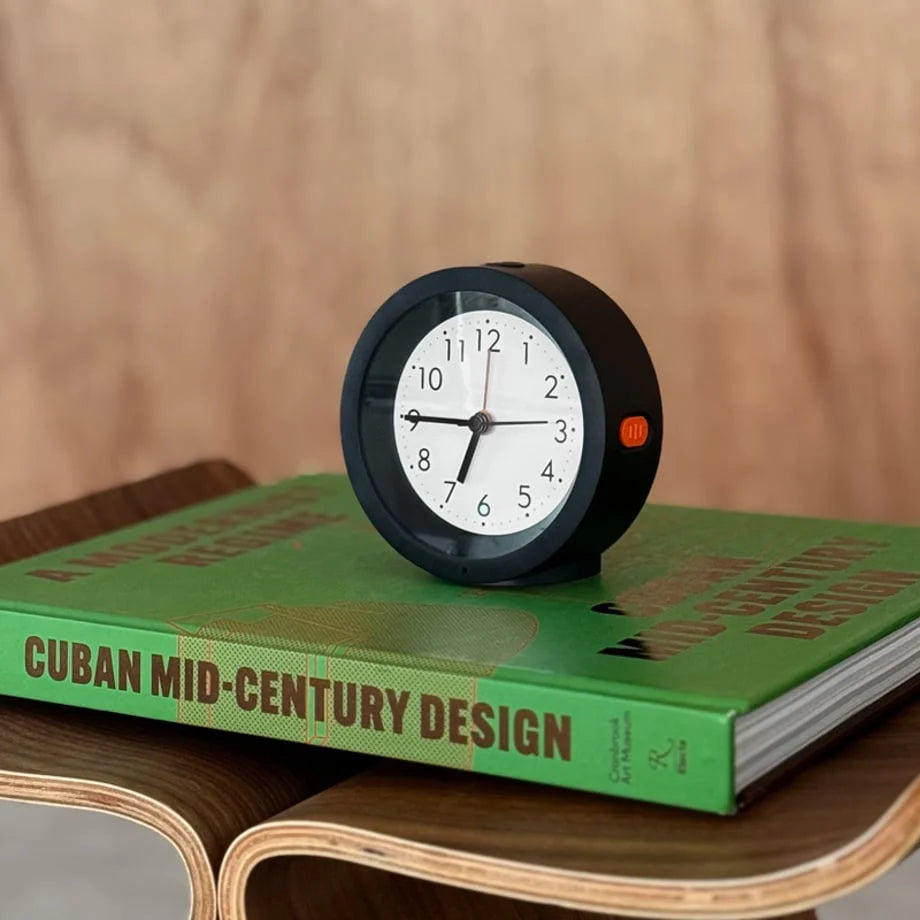 Close-up of the black Minimalist Matte Analog Alarm Clock on a mid-century design book. - RoomDen
