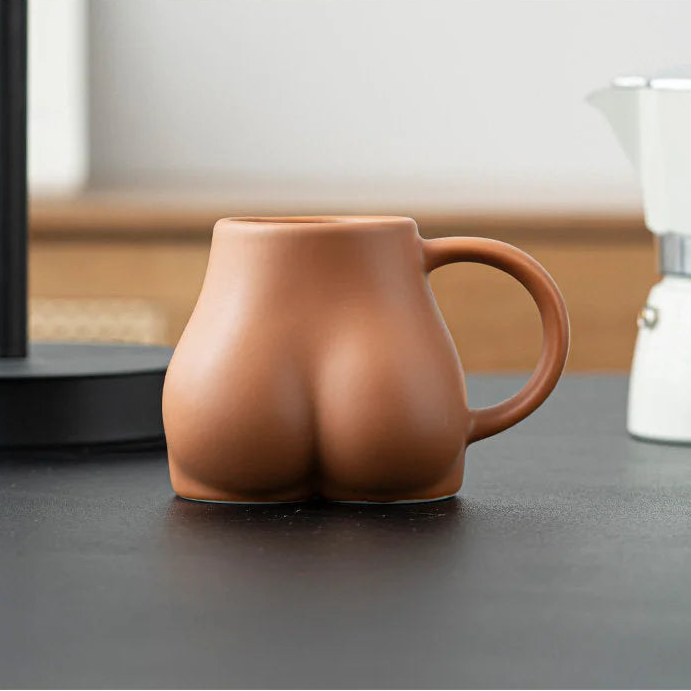 Close-up of the terracotta sculptural body ceramic mug on a black desk. - RoomDen