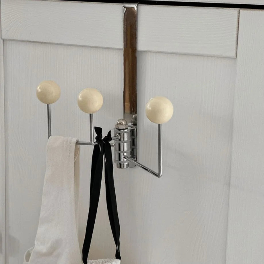 Beige variant of the Smooth Ball Tip Metal Over-the-Door Hook on a white paneled door - RoomDen
