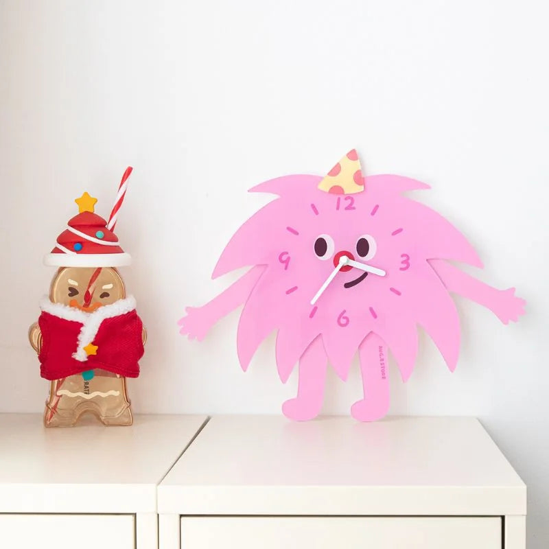 Pink Party Monster Acrylic Clock styled on a white shelf next to a cute gingerbread man cup - RoomDen.