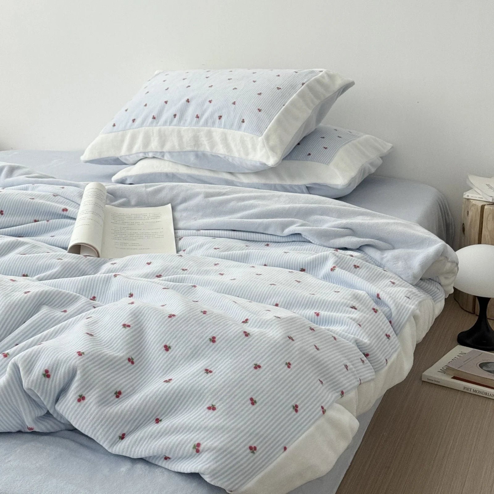A cozy bed styled with the light blue cherry pinstripe flannel fleece bedding set, showcasing the duvet cover and matching pillowcases - RoomDen.