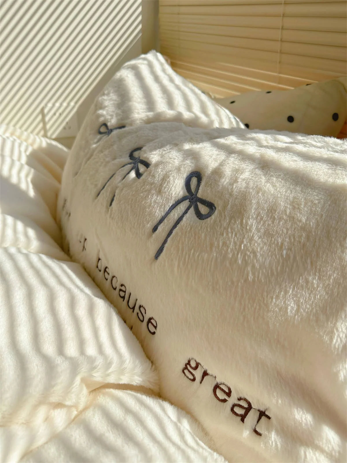 Detail shot of the embroidered text "never give up because great" on a white fleece pillowcase.