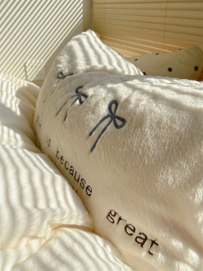 Detail shot of the embroidered text "never give up because great" on a white fleece pillowcase.