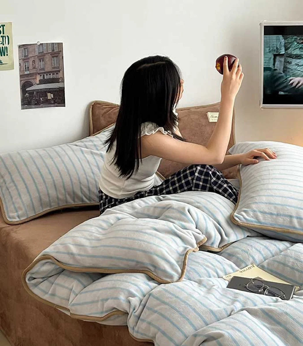 Lifestyle image of a person sitting on the Cozy Striped Flannel Fleece Bedding in Mocha Brown. - RoomDen