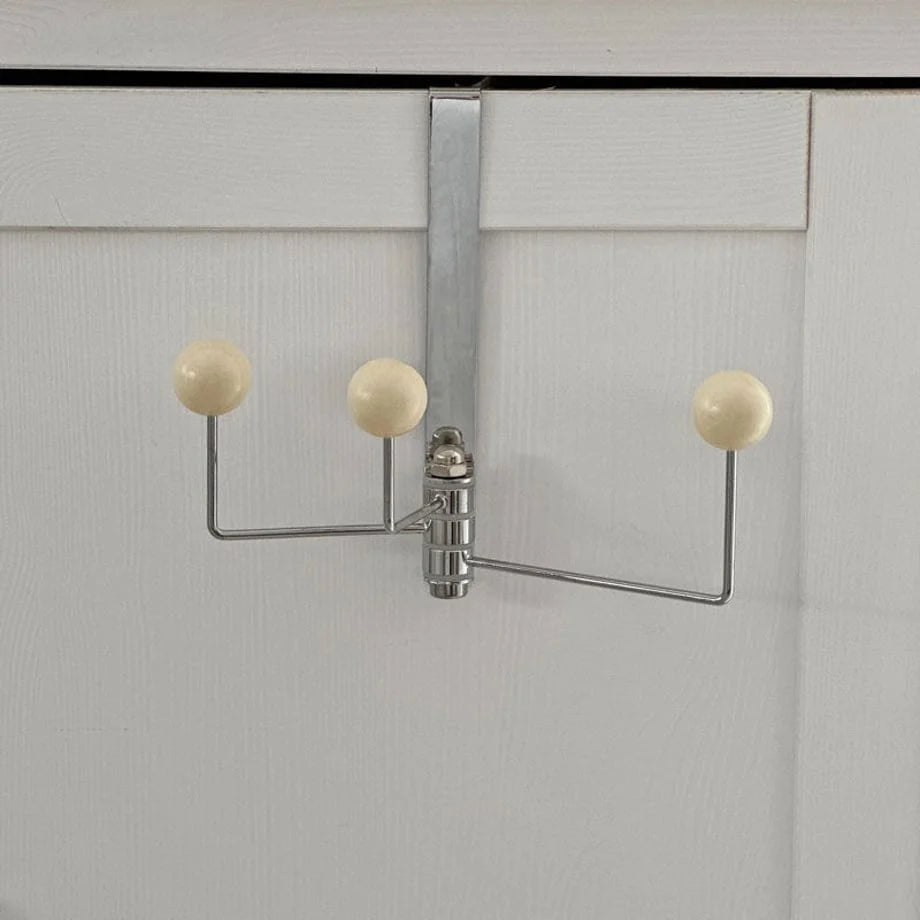 Full view of the beige metal door hook against a white door for scale - RoomDen
