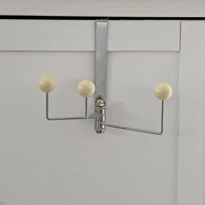 Full view of the beige metal door hook against a white door for scale - RoomDen