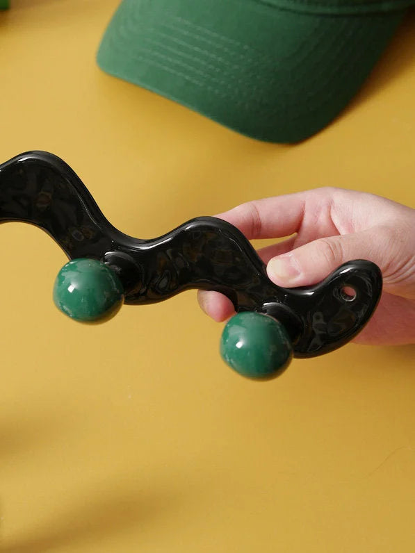 Hand holding a two-hook wavy black ceramic wall hook with green balls, showing the size and glossy texture.