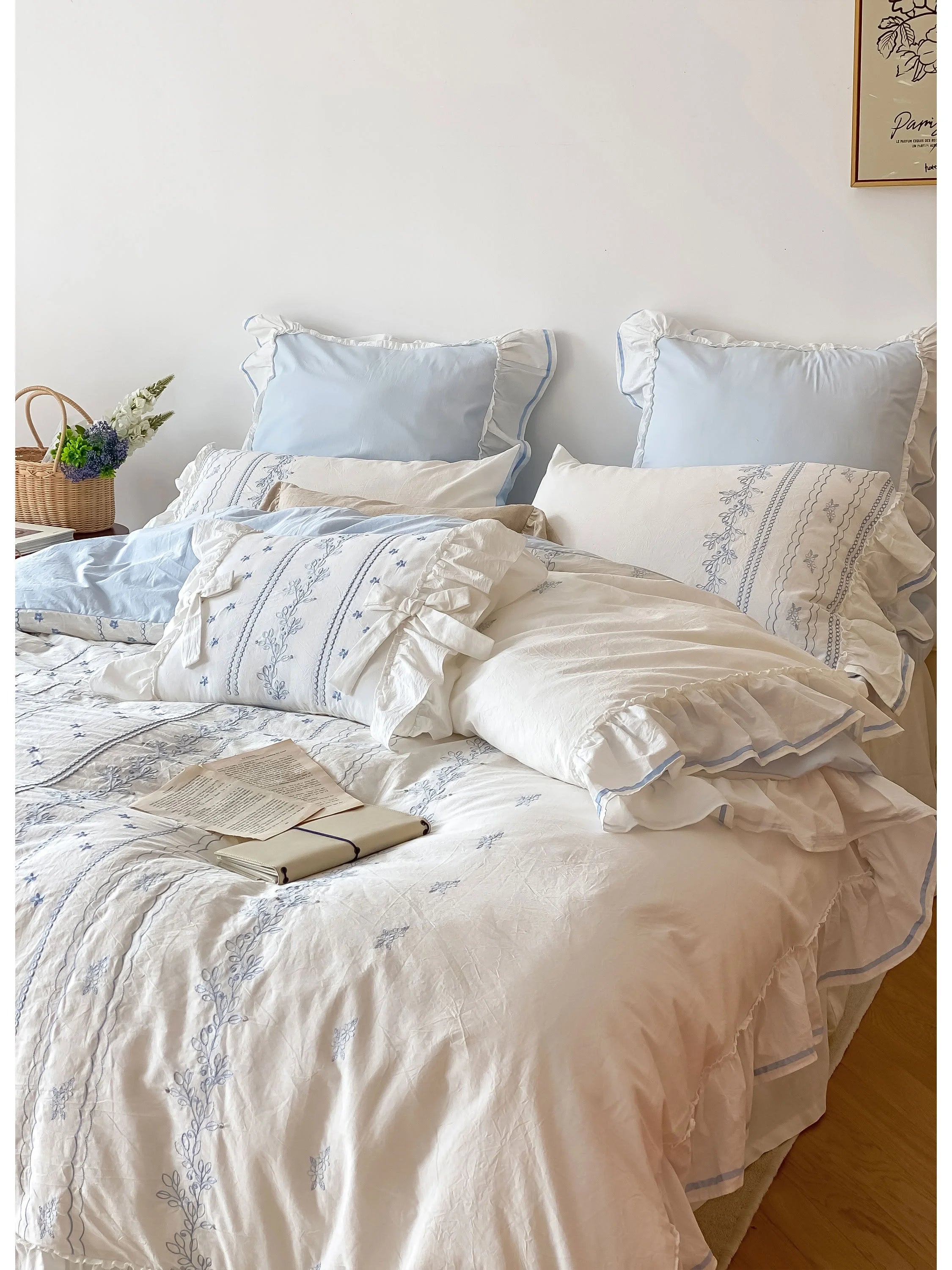 Close-up of the Ruffled Floral Vine Embroidered Bedding Set with a book resting on the plush pillows.