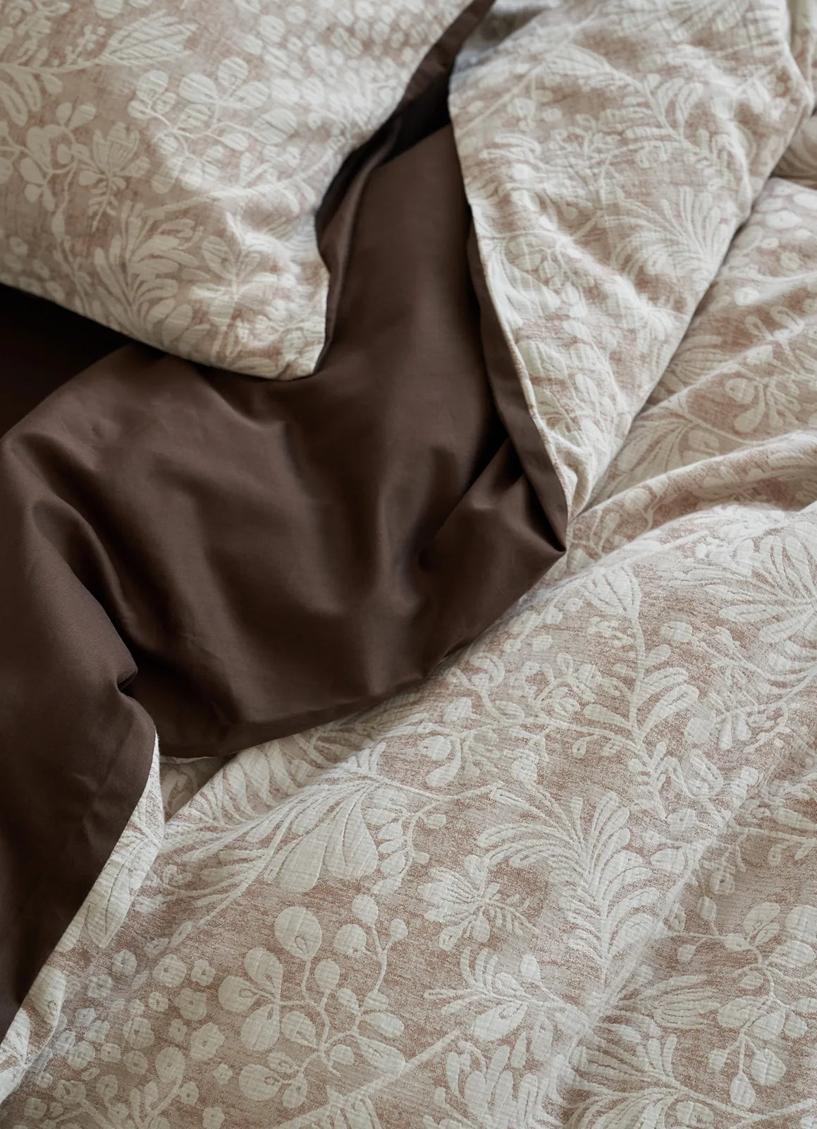 A close-up, textural shot of the taupe brown Jacquard Botanical Bedding Set, revealing the woven pattern and the rich dark brown reverse fabric - RoomDen.