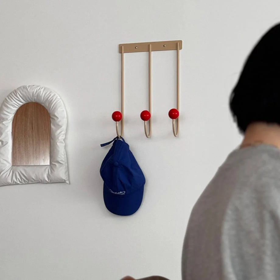 A person in a grey shirt standing near the Beige & Red decorative wall hooks. - RoomDen