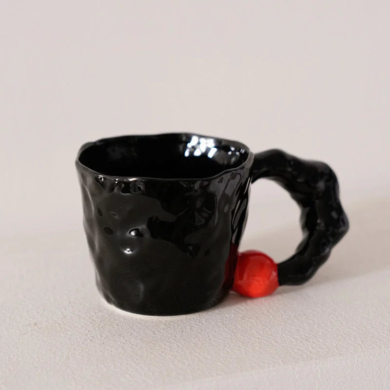 Front view of the black textured ceramic mug with a red accent on its chunky handle - RoomDen.