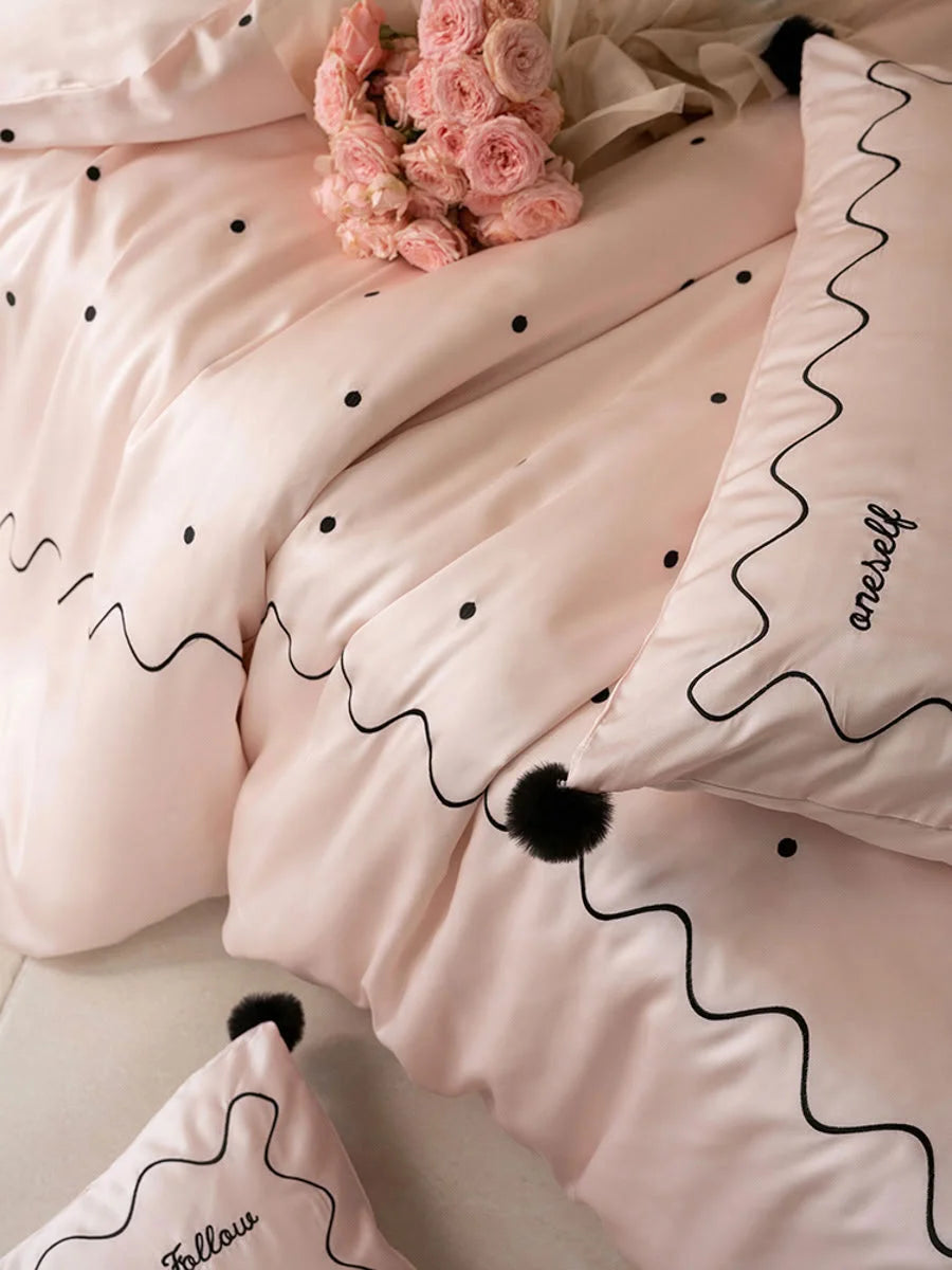 Close-up detail of the Pastel Pink & Black Tencel bedding, focusing on the black pom poms and embroidery. - RoomDen