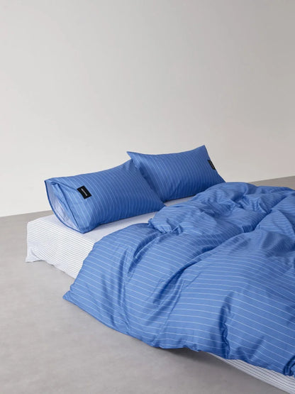 Angled view of the Denim Blue Pinstripe bedding, showing the texture of the washed cotton duvet cover and pillowcases - RoomDen.