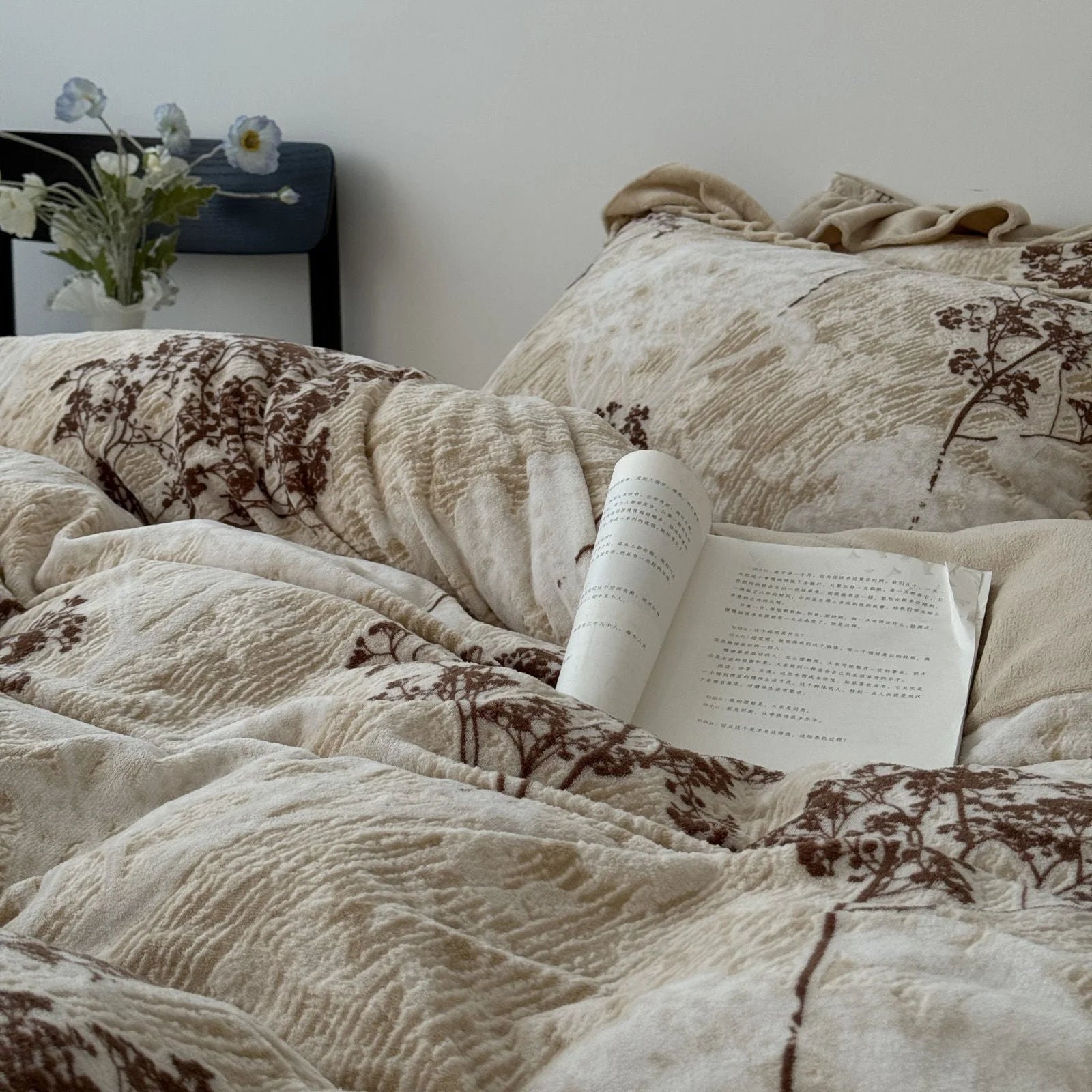 A styled shot of the cozy floral branch bedding with a book resting on the plush duvet cover, showcasing its soft texture.