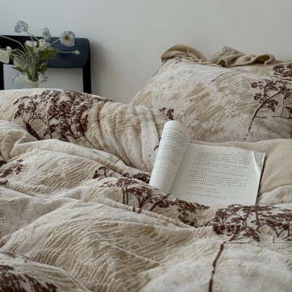 A styled shot of the cozy floral branch bedding with a book resting on the plush duvet cover, showcasing its soft texture.