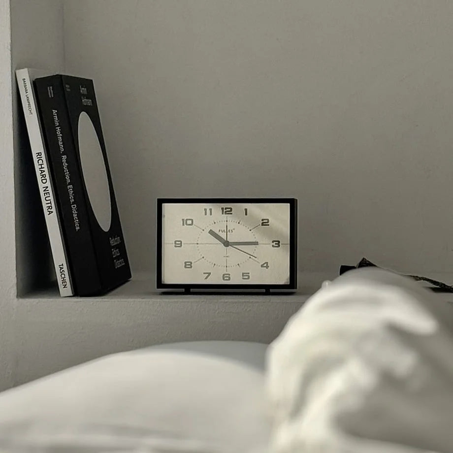 Softly lit view of the Matte Black Retro Table Clock in a cozy bedroom setting.