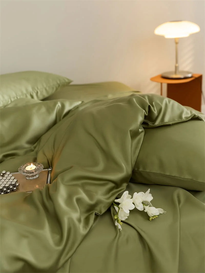 Angled close-up of the draped olive green duvet cover, showing its cooling Tencel sheen with a candle and flowers - RoomDen.