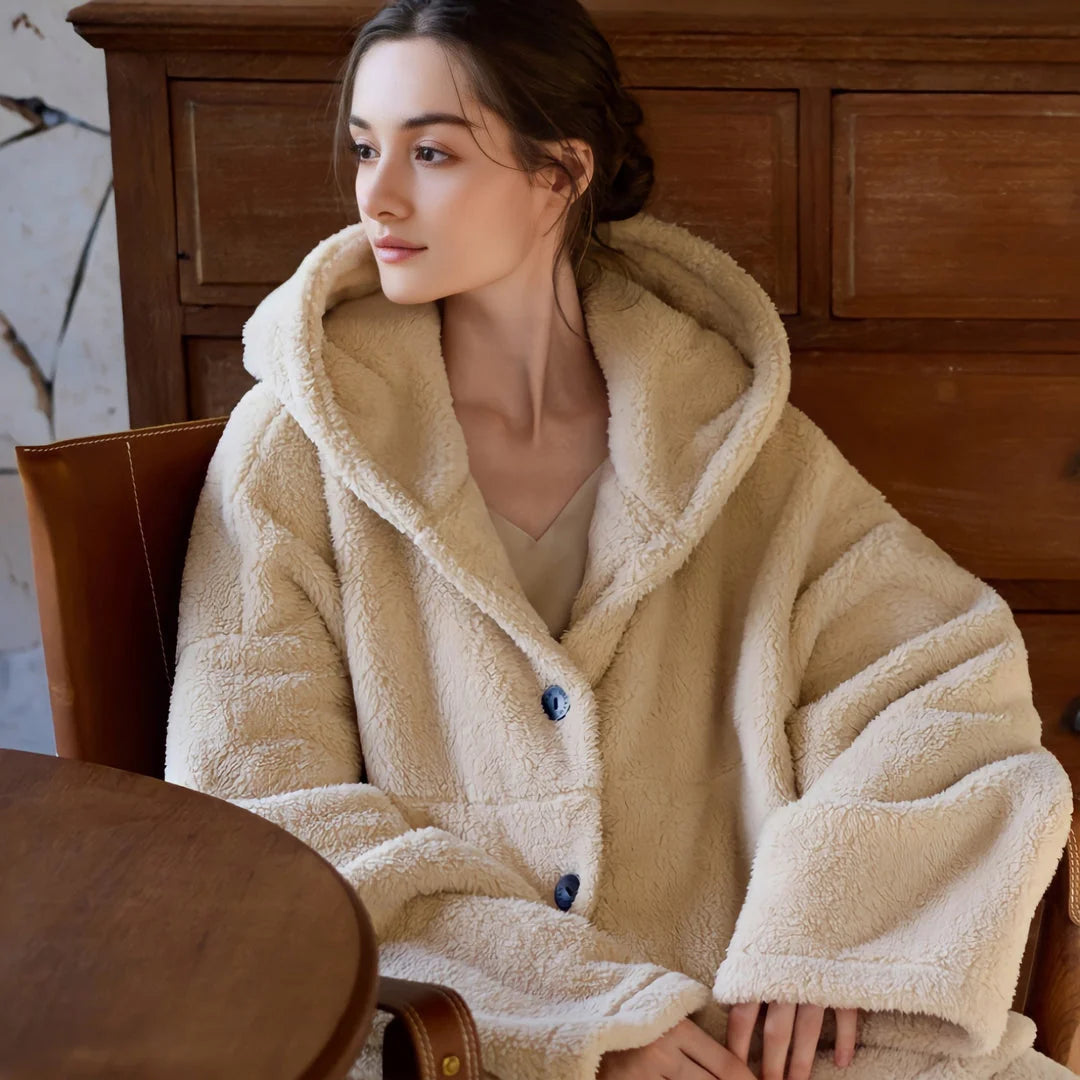 Model sitting in a leather chair wearing the cozy beige hooded fleece pajama set. - RoomDen