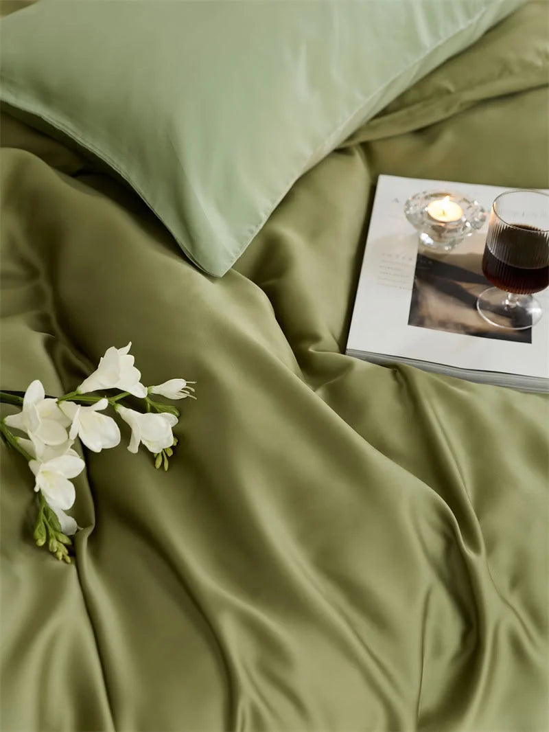 Detail shot of the olive green Tencel bedding with white flowers and a book, highlighting the fabric's smooth drape - RoomDen.