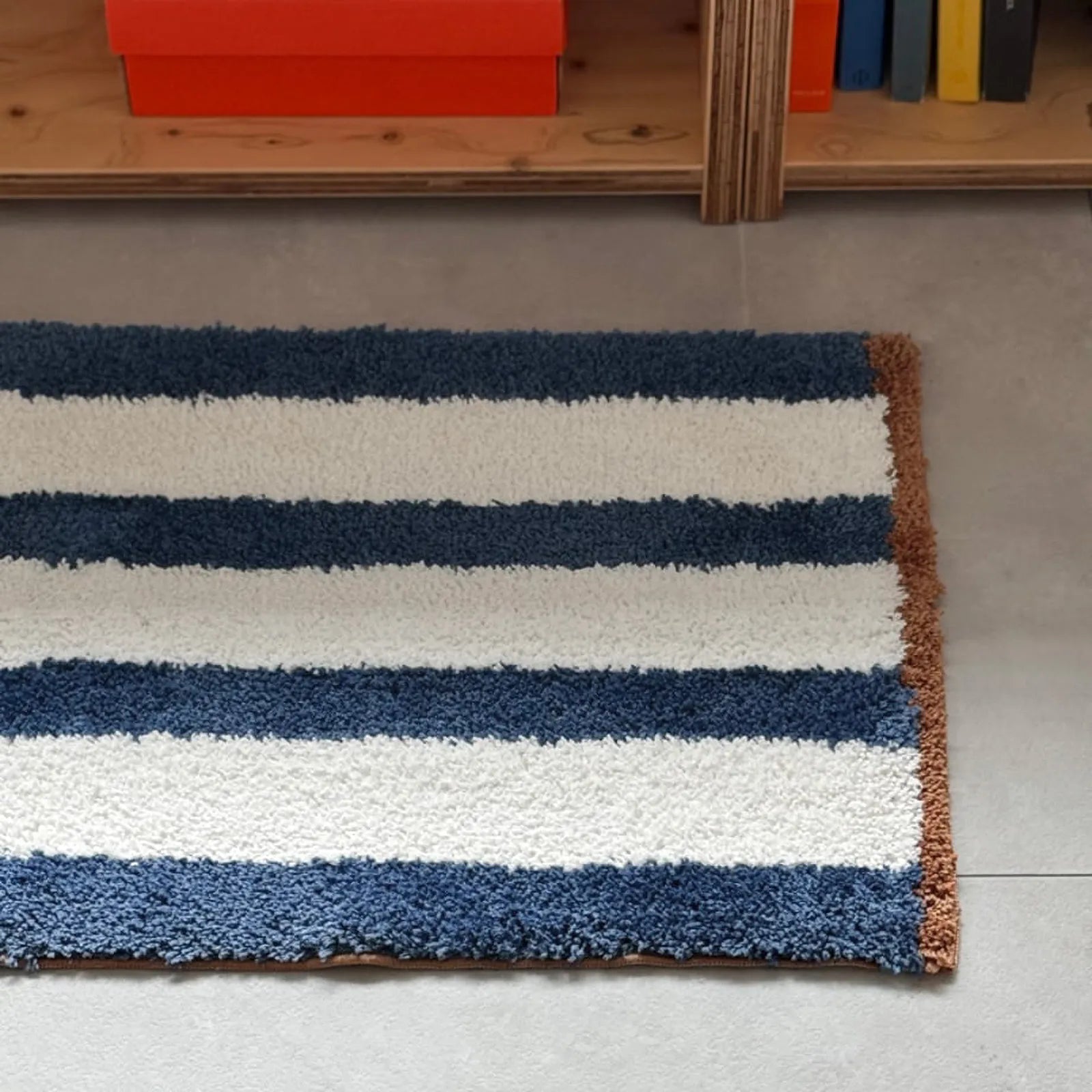 Top-down full view of rectangular blue and white striped rug with brown edges - RoomDen