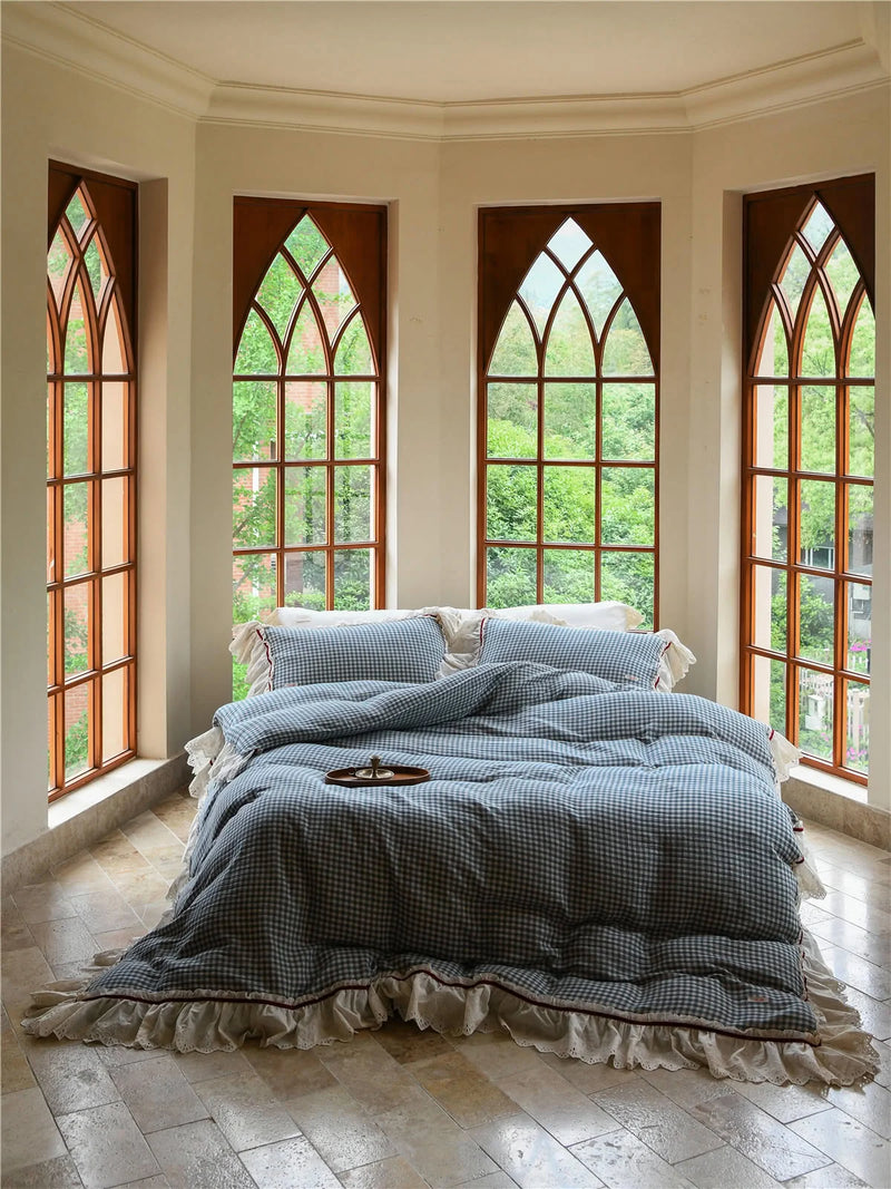 Full view of the blue gingham ruffle bedding set on a bed in a bay window area, soft cottagecore bedroom decor. — RoomDen
