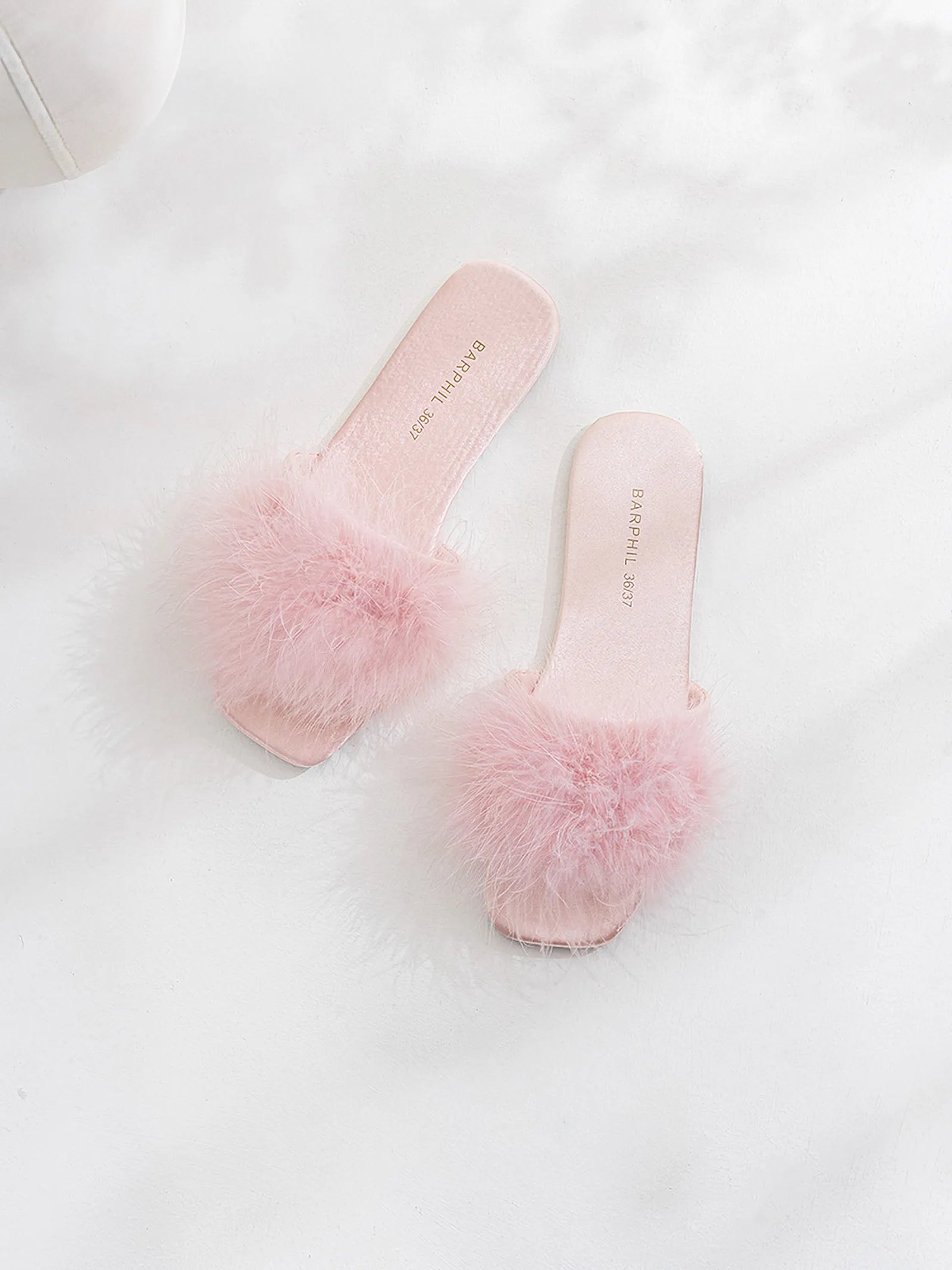 Pair of lavender fluffy slippers on white surface - RoomDen