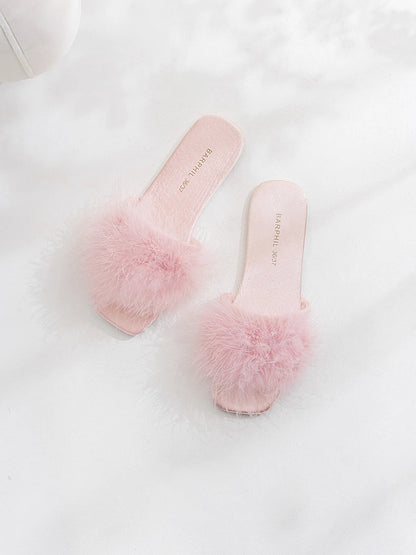 Pair of lavender fluffy slippers on white surface - RoomDen